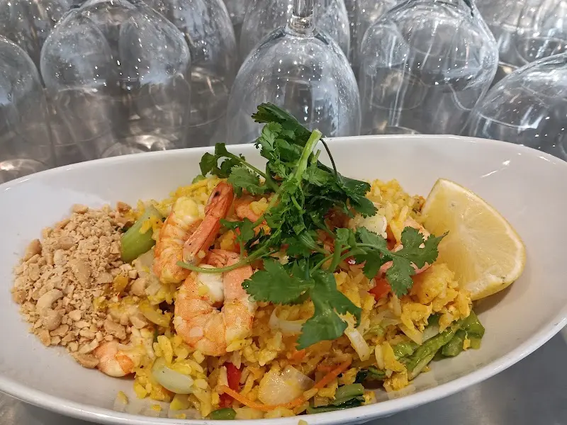 Arroz frito con gambas, cacahuete picado, cilantro y limón en una fuente blanca