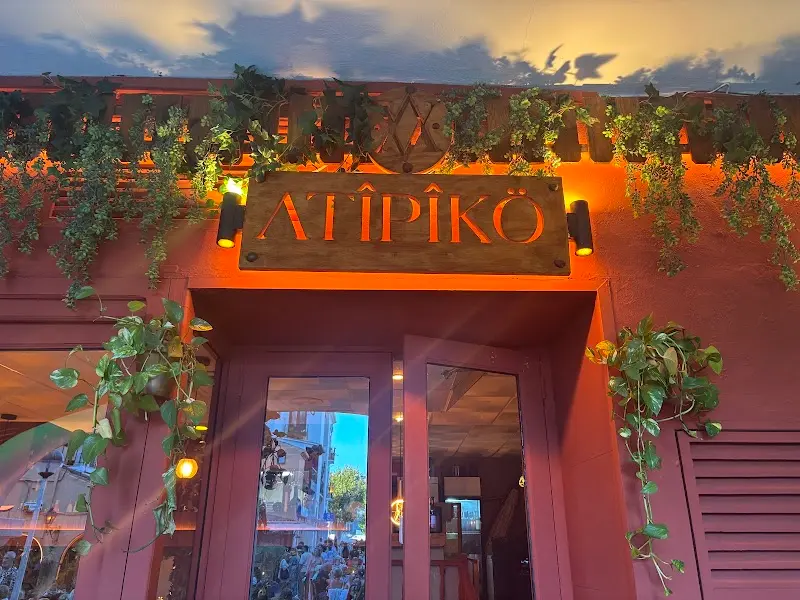 Rótulo de madera iluminado de Atipiko sobre la puerta, al atardecer