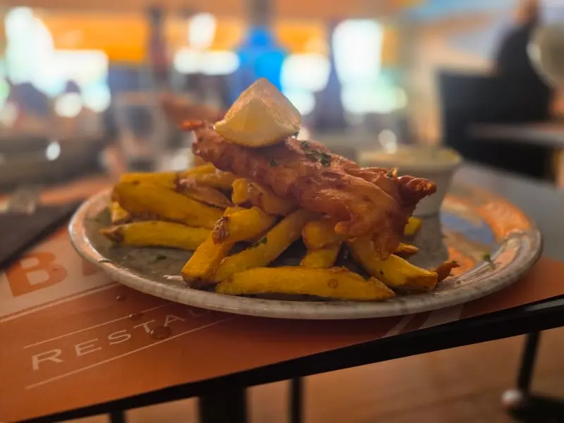 Pescado rebozado con patatas fritas y limón sobre la mesa del restaurante