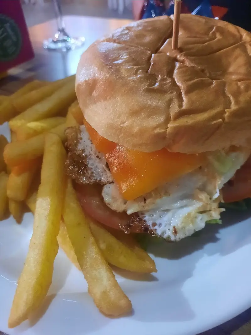 Hamburguesa con huevo frito, queso, tomate y lechuga junto a patatas fritas