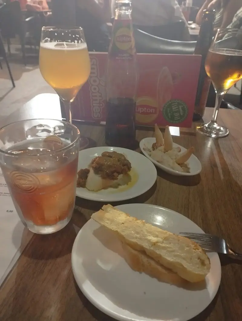 Tapas de tortilla, carne en salsa y un platillo de aperitivo con cervezas en la mesa