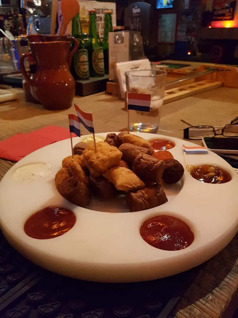 Bandeja de bitterballen y croquetas holandesas con salsas y banderitas de Países Bajos