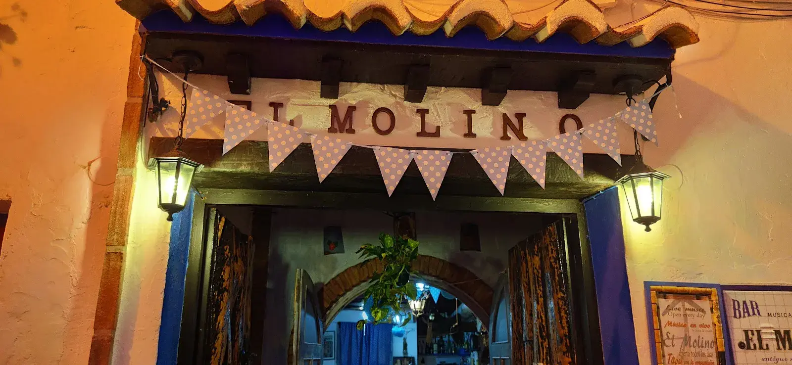 Entrada de El Molino de noche, con faroles y banderines sobre la puerta