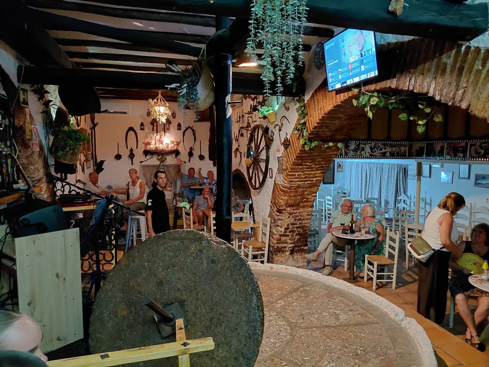 Interior de El Molino con la gran piedra de molino y mesas bajo los arcos