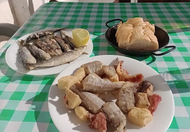 Sardinas a la plancha, fritura de pescado variado y pan en un mantel de cuadros verdes