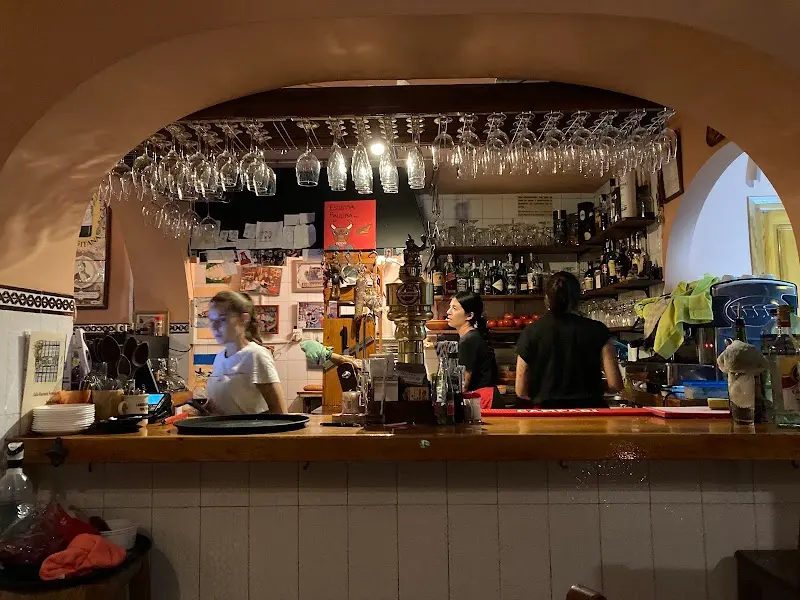 Barra bajo un arco con copas colgadas y el personal trabajando detrás