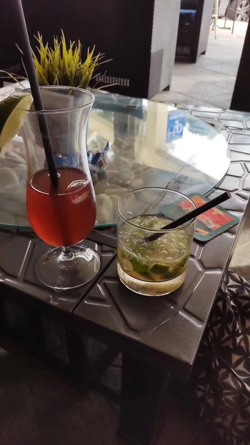 Dos cócteles en la terraza, uno rojo en copa alta y otro con lima y hielo picado