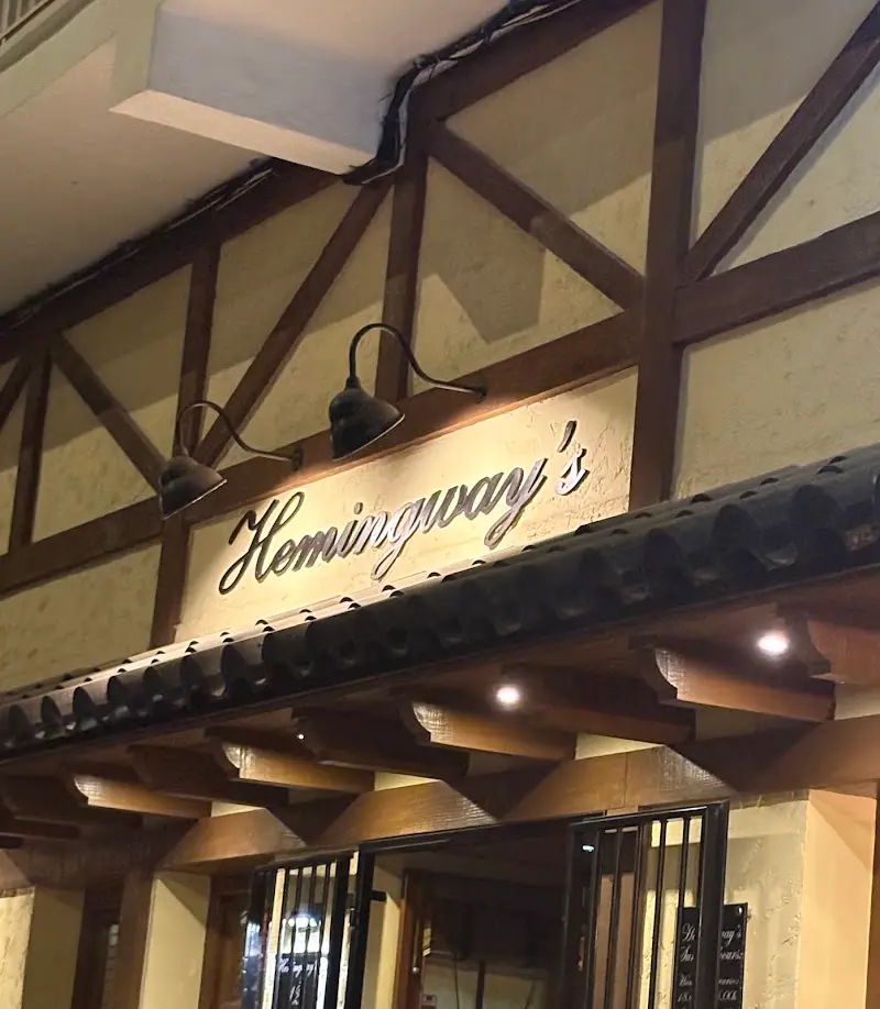 Rótulo de Hemingway's sobre la entrada con vigas de madera, tejadillo y farolillos