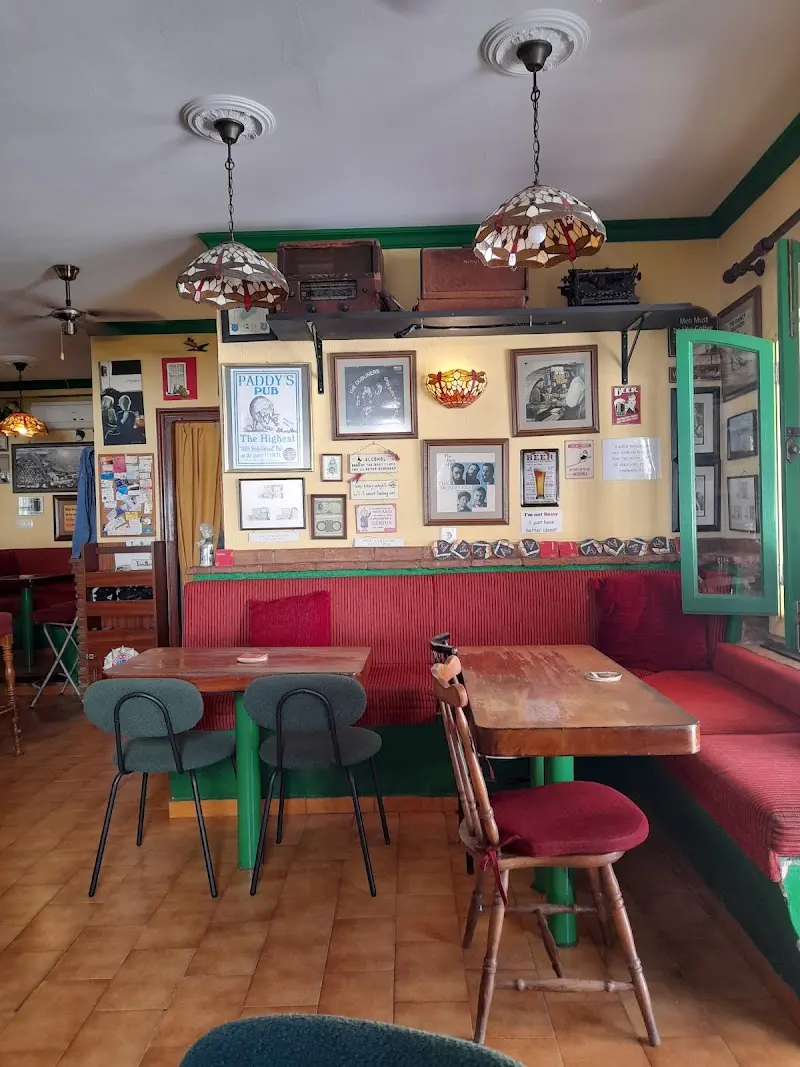 Rincón con banco rojo, mesas de madera y cuadros antiguos en la pared del pub