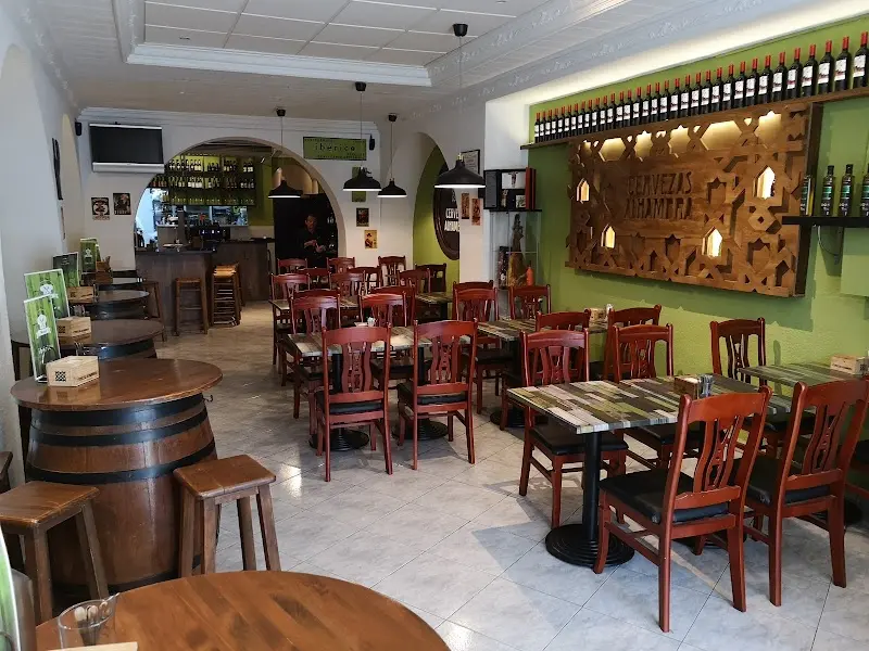 Comedor con sillas de madera roja, mesas barril y estantería de botellas de vino