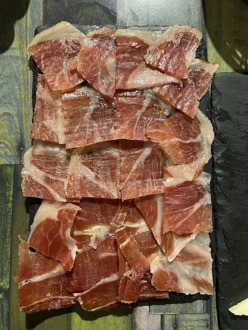 Tabla de jamón ibérico cortado en lonchas finas sobre pizarra