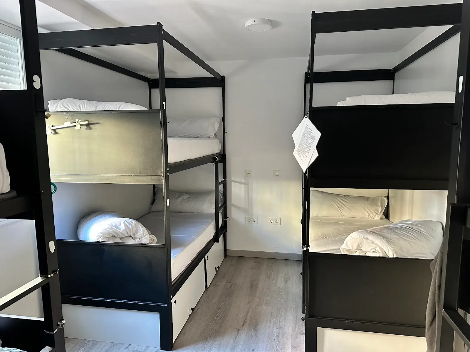 Dormitorio compartido con literas negras y ropa de cama blanca