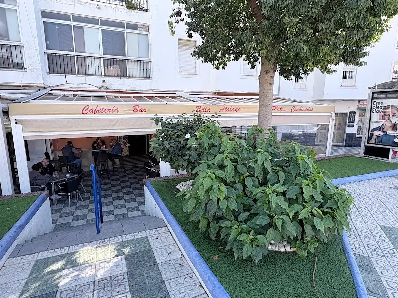 Fachada de la cafetería con rótulo de platos combinados, terraza y un árbol delante