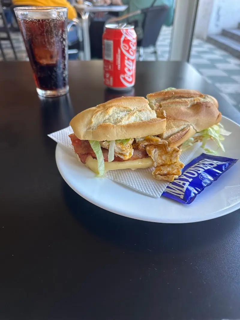 Bocadillo con bacon, huevo, queso y lechuga junto a un refresco de cola