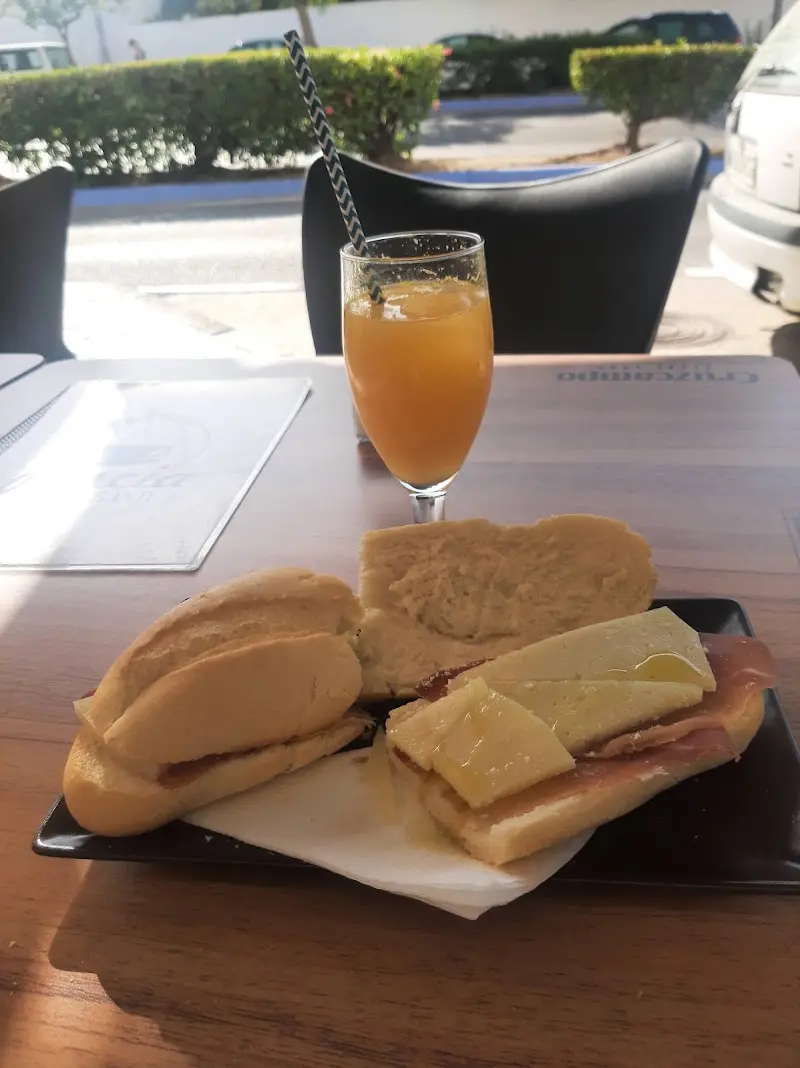 Desayuno con tostada de jamón y queso con aceite y un zumo de naranja