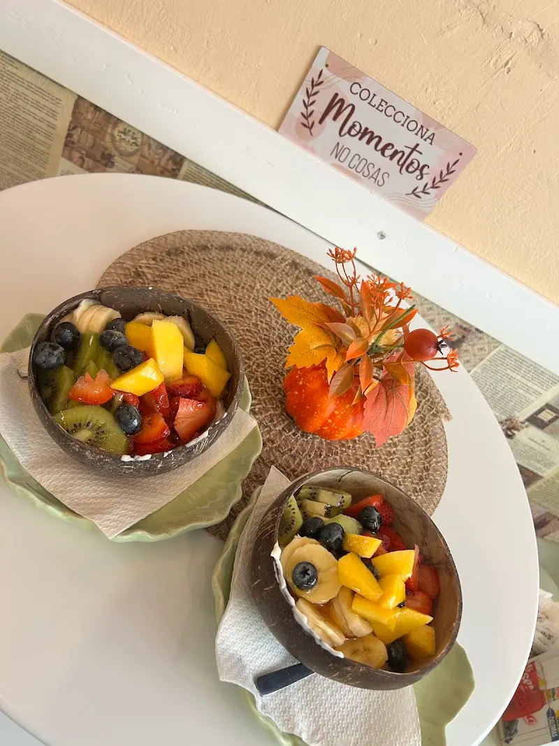 Dos boles de coco con macedonia de mango, kiwi, fresas y arándanos sobre una mesa blanca