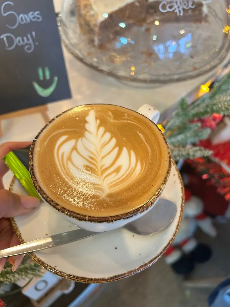 Capuchino con arte latte en forma de hoja y decoración navideña en la barra