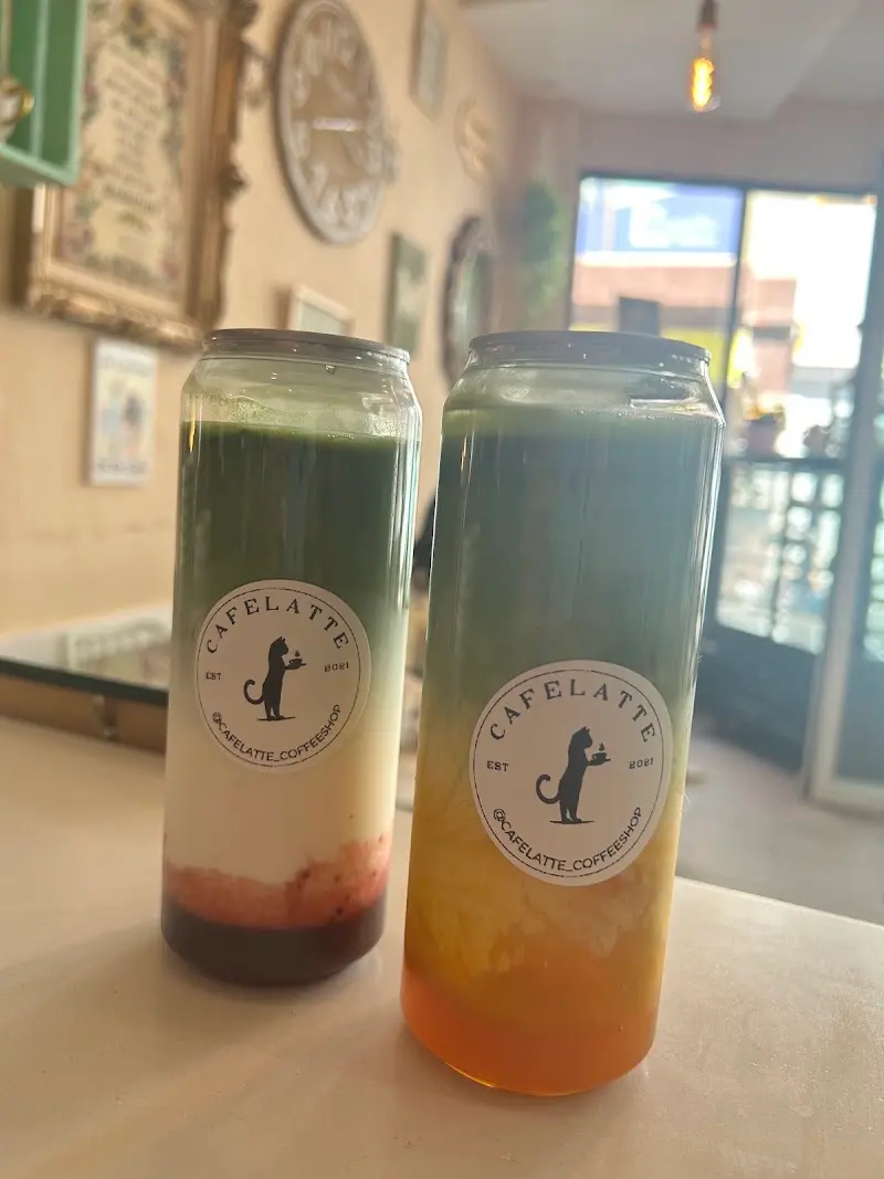 Dos bebidas de matcha en vaso lata con el logo del gato de CafeLatte, una con fresa y otra con mango