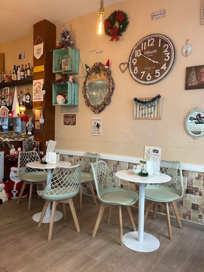 Interior de la cafetería con sillas verde menta, mesas redondas, gran reloj de pared y adornos navideños
