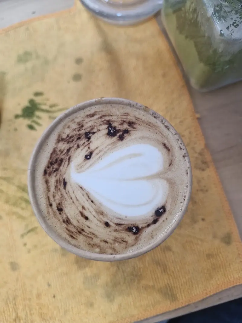 Café con arte latte en forma de corazón en un vaso para llevar