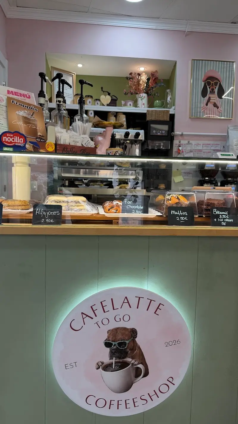 Mostrador con dulces y precios en pizarritas sobre el logo luminoso de la cafetería
