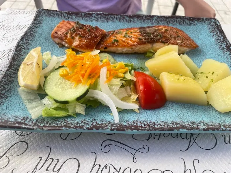 Salmón a la plancha con patatas cocidas, ensalada y limón en fuente azul