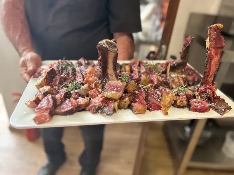 Bandeja de chuletón a la brasa troceado con hueso y ramitas de romero