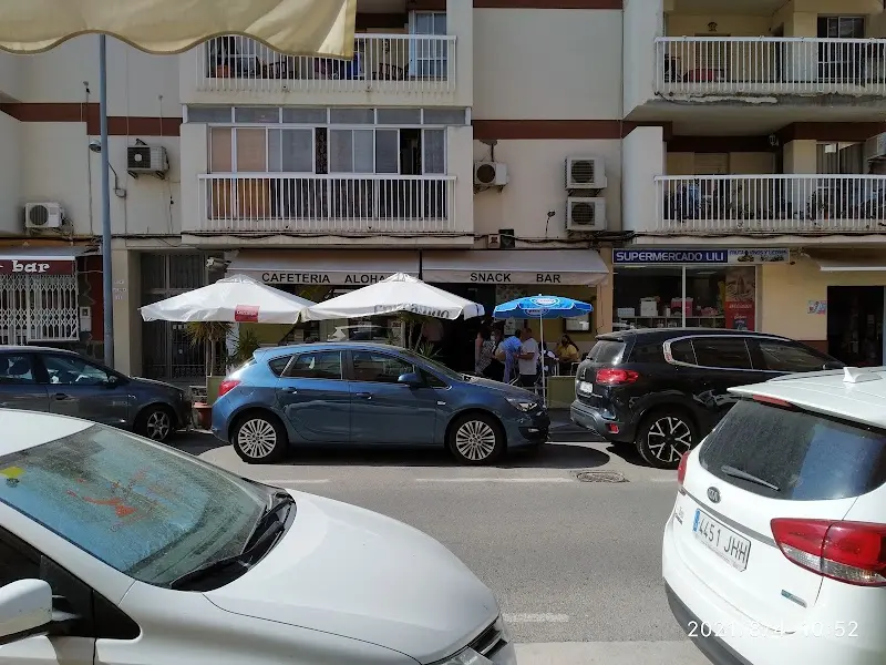 Fachada de la cafetería y snack bar con sombrillas blancas, vista desde el otro lado de la calle