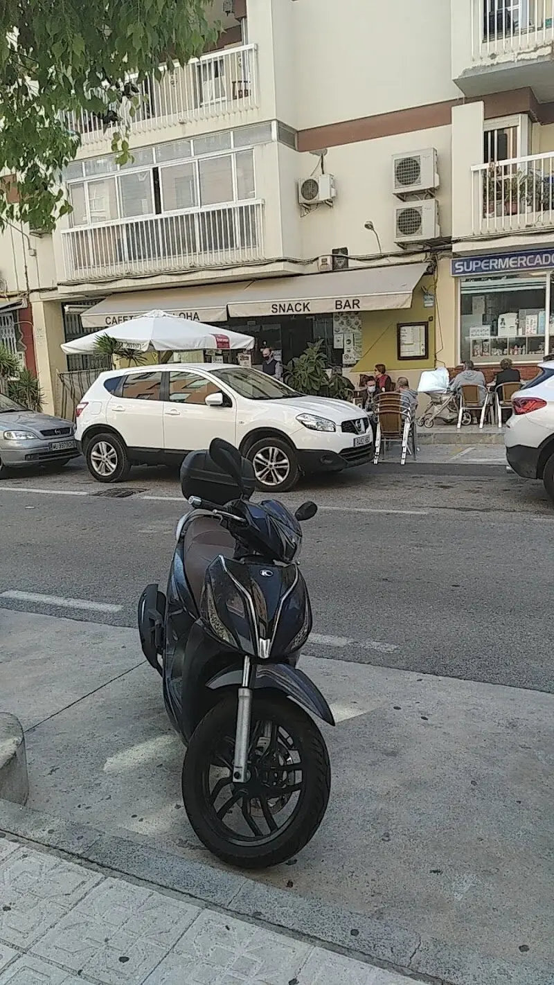Terraza del snack bar con clientes sentados y una moto aparcada en primer plano