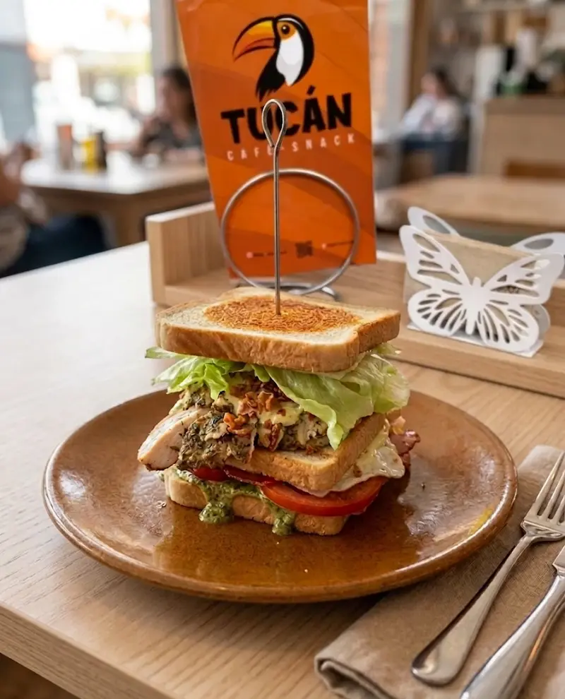 Sándwich club con pollo, lechuga, tomate y huevo pinchado con el cartel del Tucán