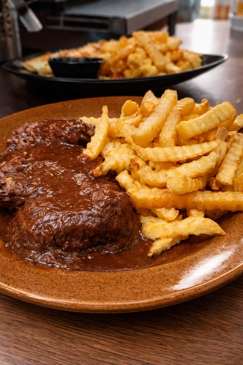 Carne en salsa con patatas fritas onduladas en plato de barro