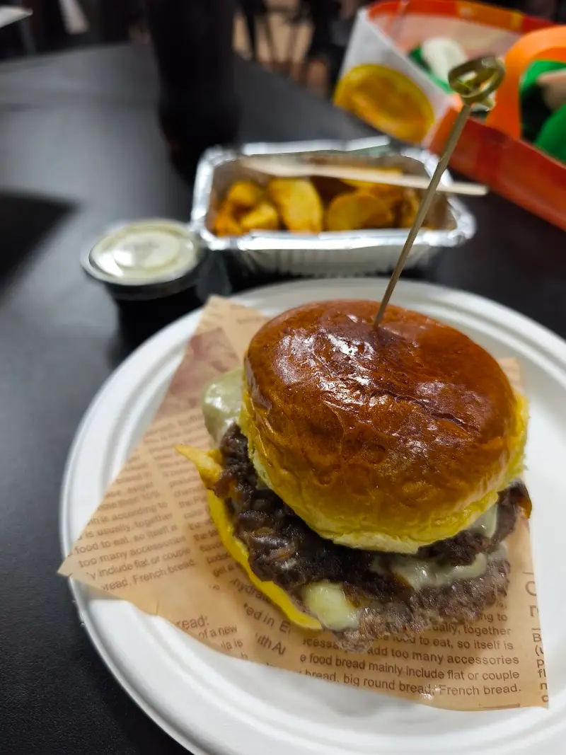 Hamburguesa con queso fundido y cebolla en pan brioche, con patatas gajo de acompañamiento