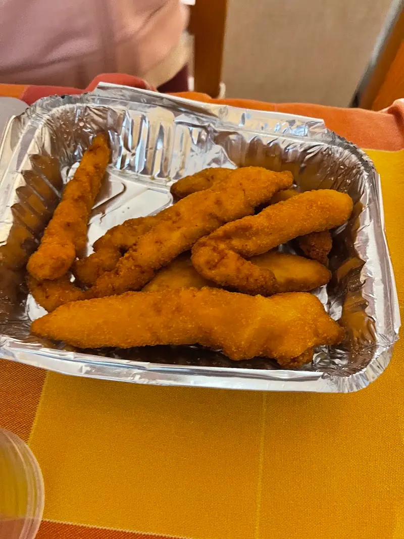 Tiras de pollo empanado en una bandeja de aluminio para llevar