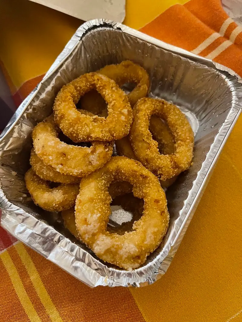 Aros de cebolla rebozados en una bandeja de aluminio sobre un mantel naranja