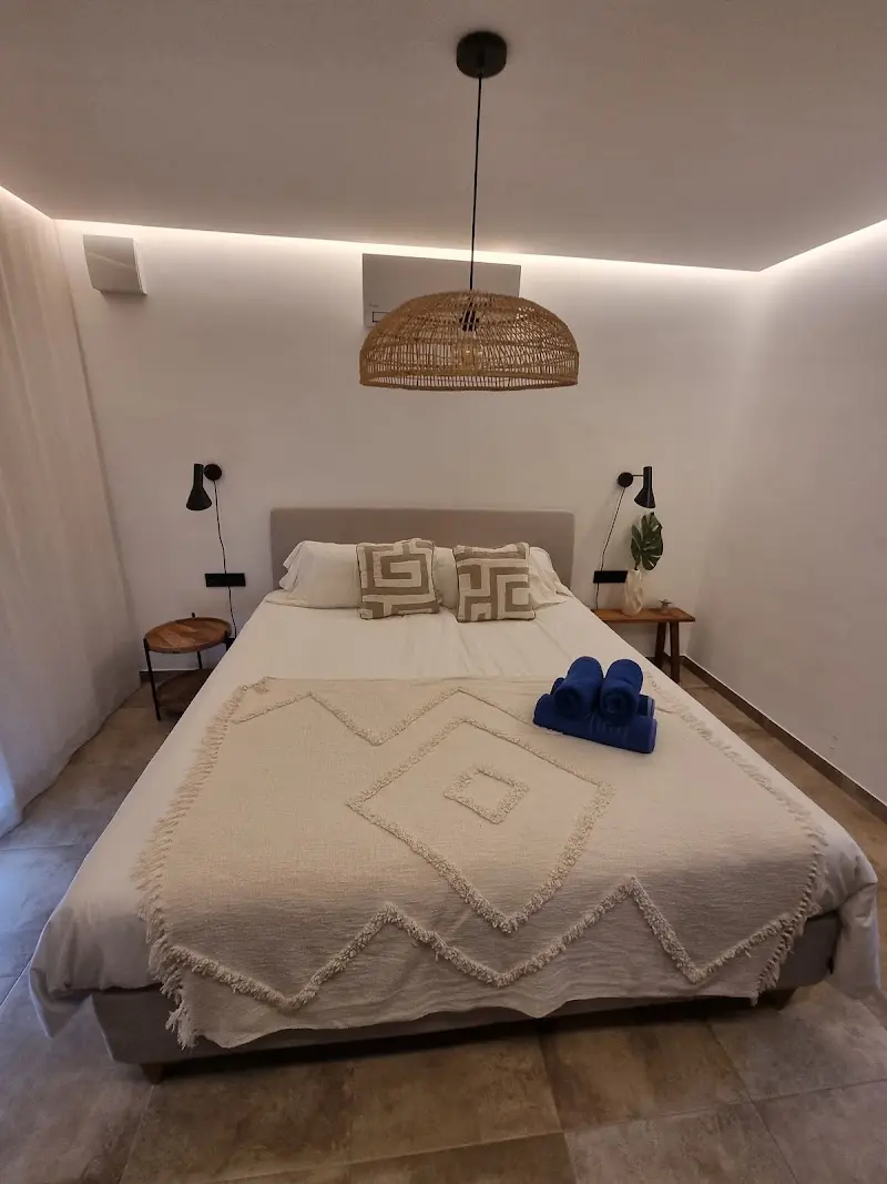 Dormitorio con cama de matrimonio, colcha de flecos, lámpara de mimbre y toallas azules