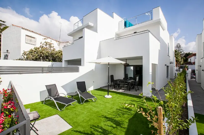 Casa blanca moderna de Casas de la Seda con jardín de césped, tumbonas y sombrilla