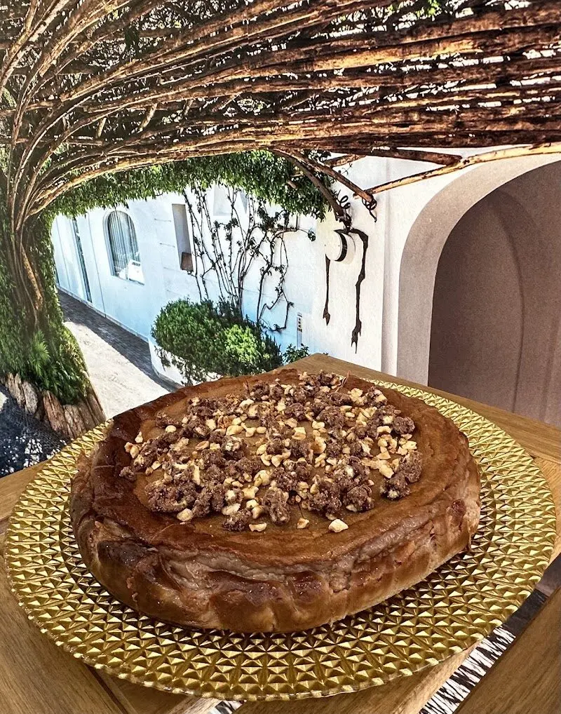 Tarta de queso con cobertura de chocolate y avellanas troceadas en bandeja dorada