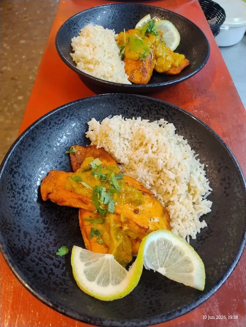 Dos platos de pollo con salsa de curry, arroz blanco y rodajas de limón