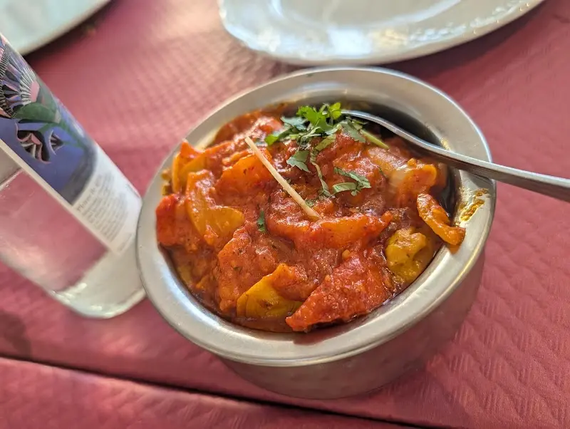 Curry de verduras con salsa de tomate y cilantro en un cuenco metálico