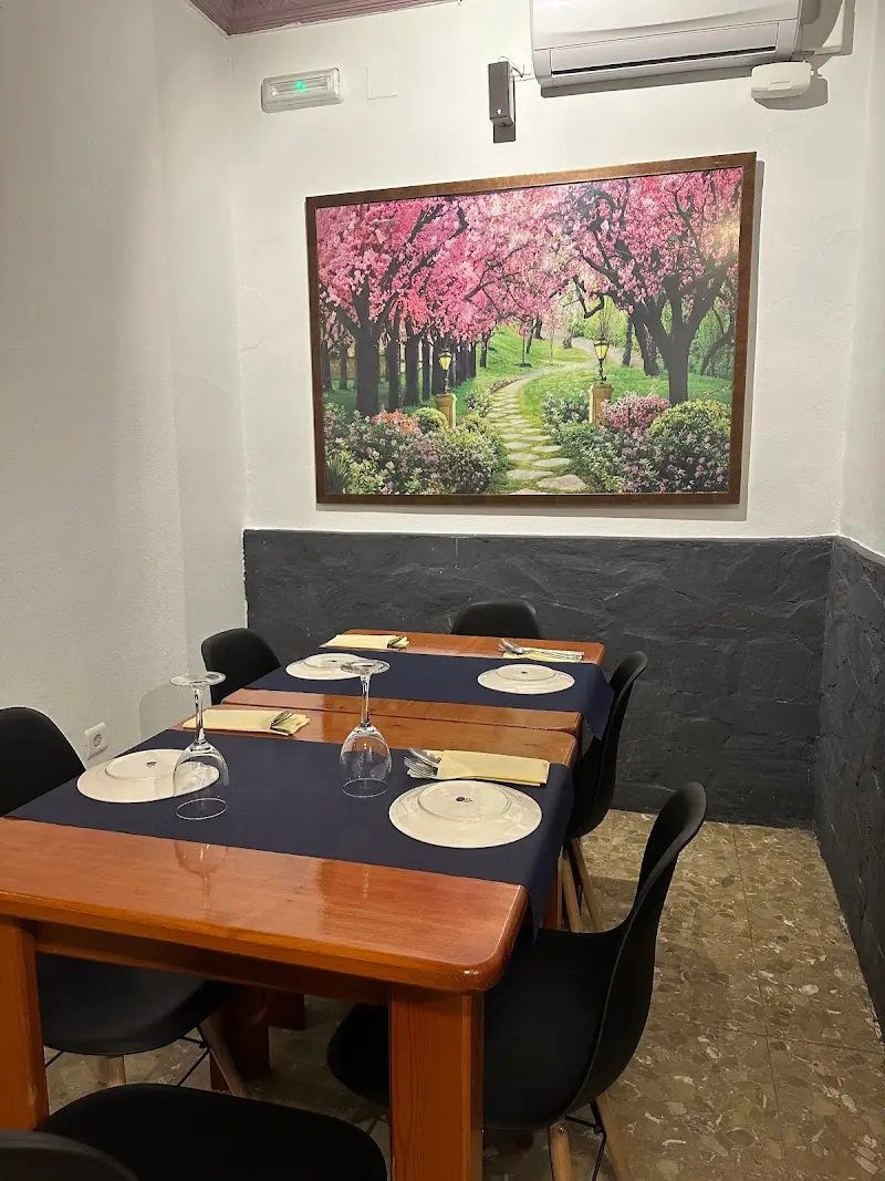 Comedor interior con mesas de madera preparadas y un cuadro de cerezos en flor