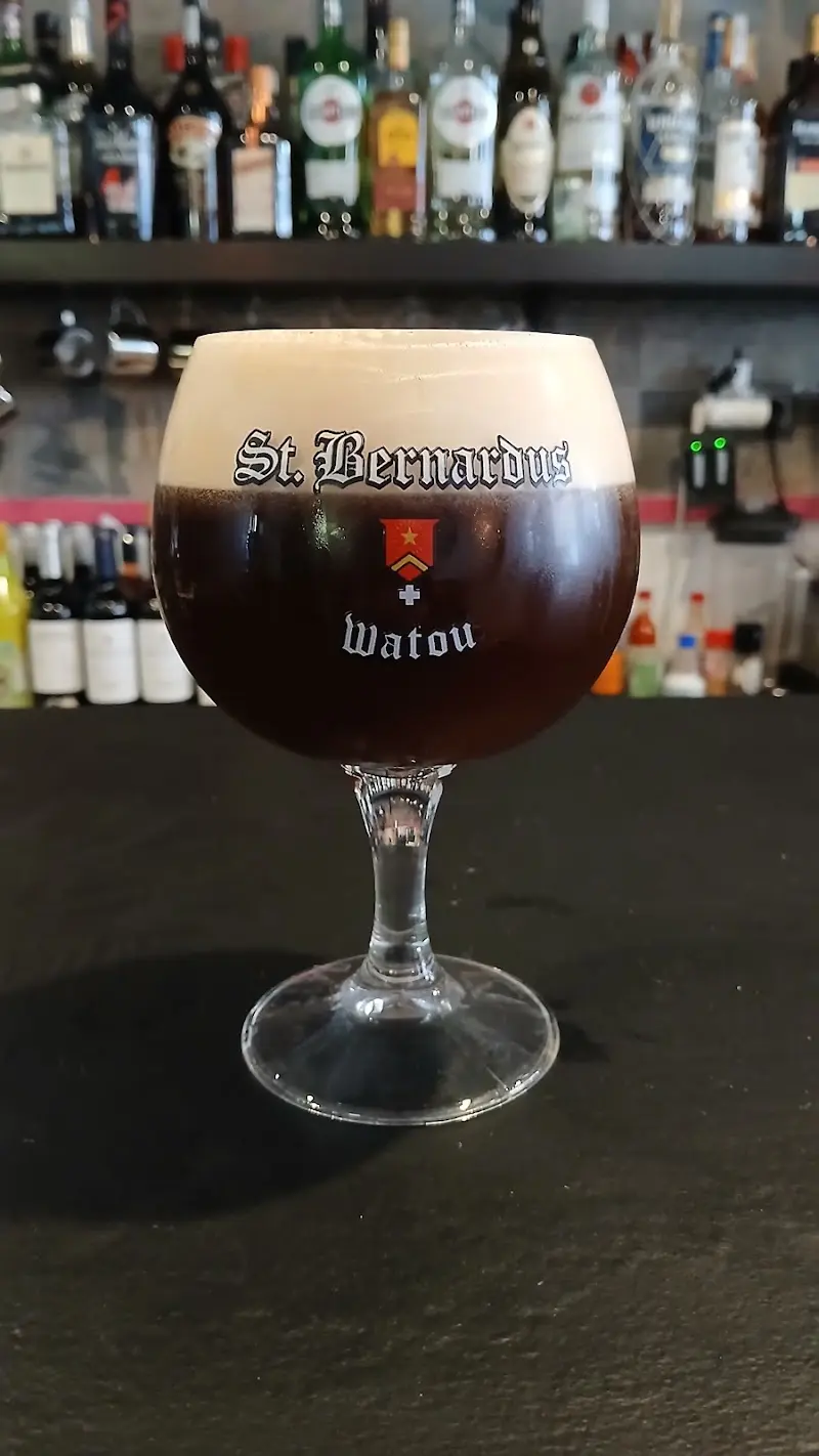 Copa de cerveza belga St. Bernardus oscura con espuma sobre la barra del bar
