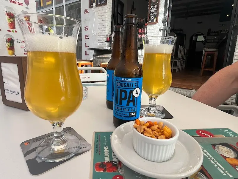Dos copas de cerveza, botellas de IPA y un cuenco de frutos secos en la terraza