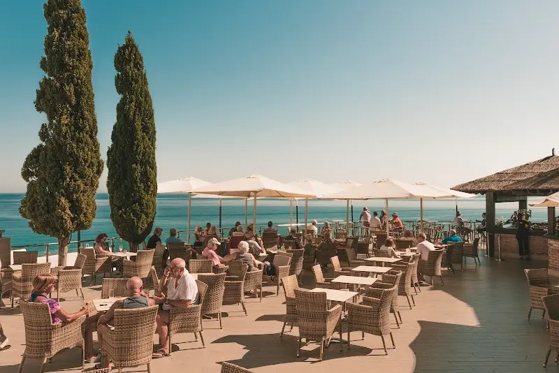 Terraza de Cochran's con sillas de mimbre, cipreses y vistas al Mediterráneo