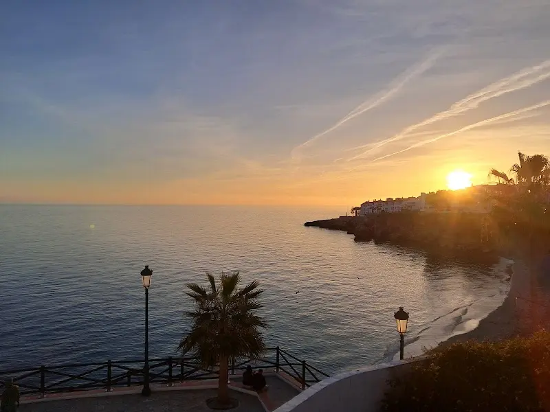 Atardecer sobre el mar desde el mirador, con una farola y una palmera en primer plano