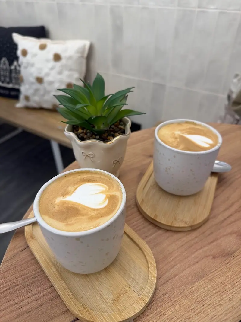 Dos cafés con leche con dibujo de corazón en tazas sobre bandejitas de bambú