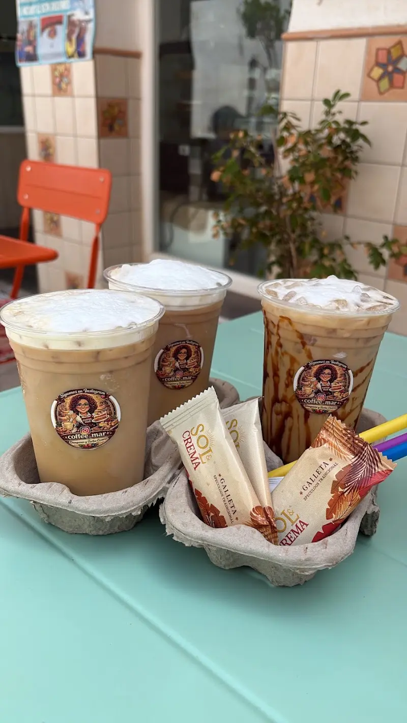 Tres cafés con hielo para llevar con galletas en un portavasos sobre mesa turquesa