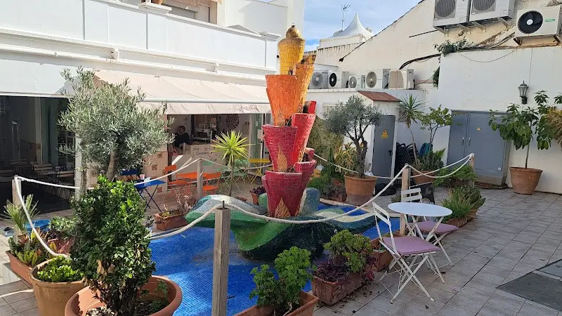 Patio de la galería comercial con fuente de mosaico, plantas en macetas y la terraza del café