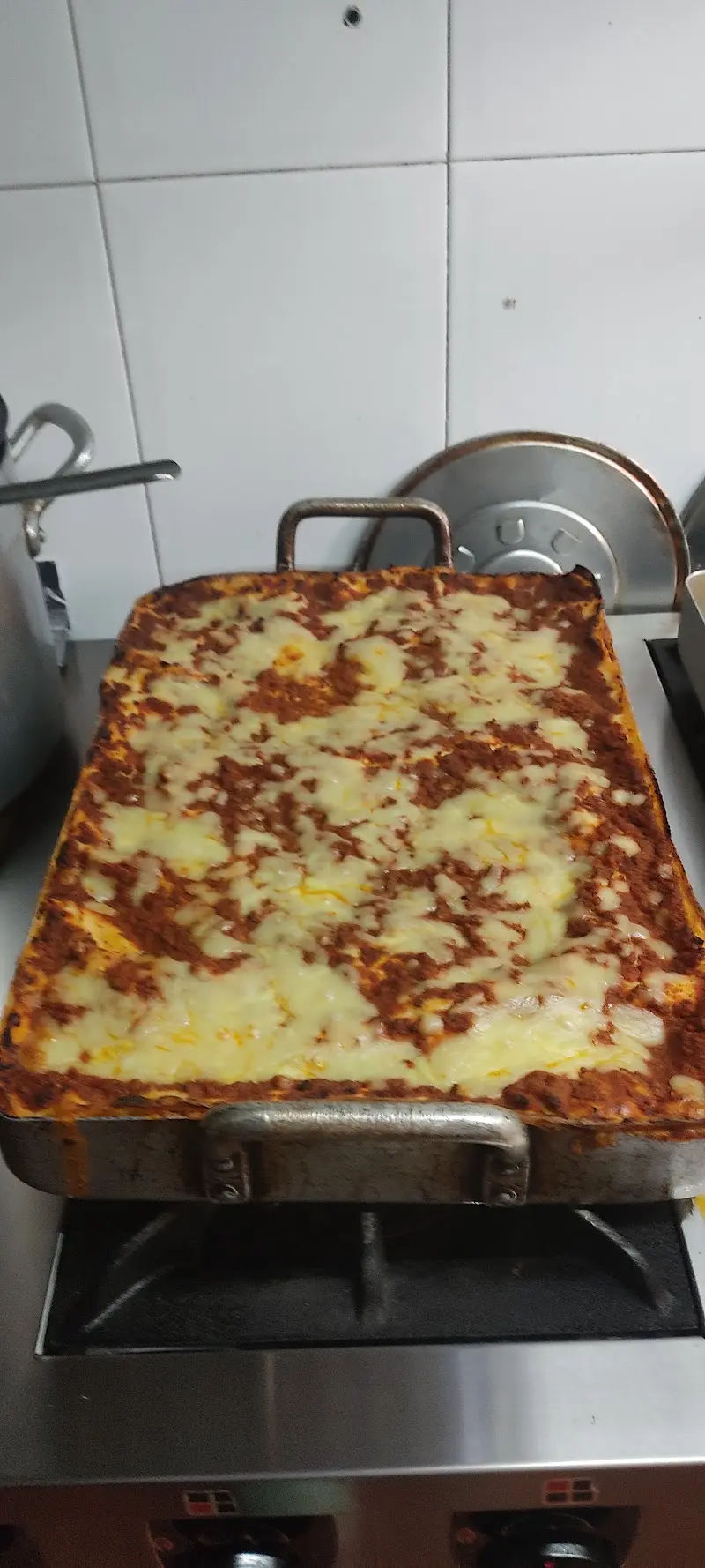 Bandeja de lasaña recién gratinada con queso fundido en la cocina