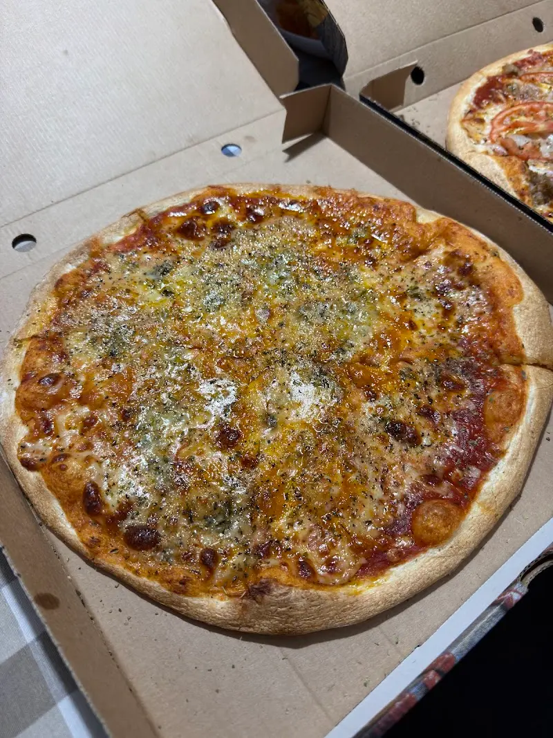 Pizza de queso con orégano en su caja de cartón para llevar