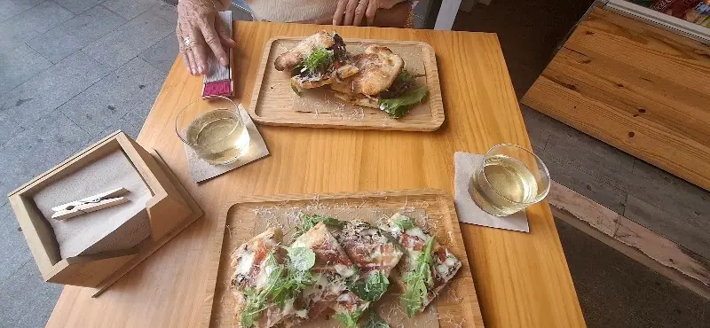 Dos tablas de pizza en la mesa de la terraza, con copas de vino blanco